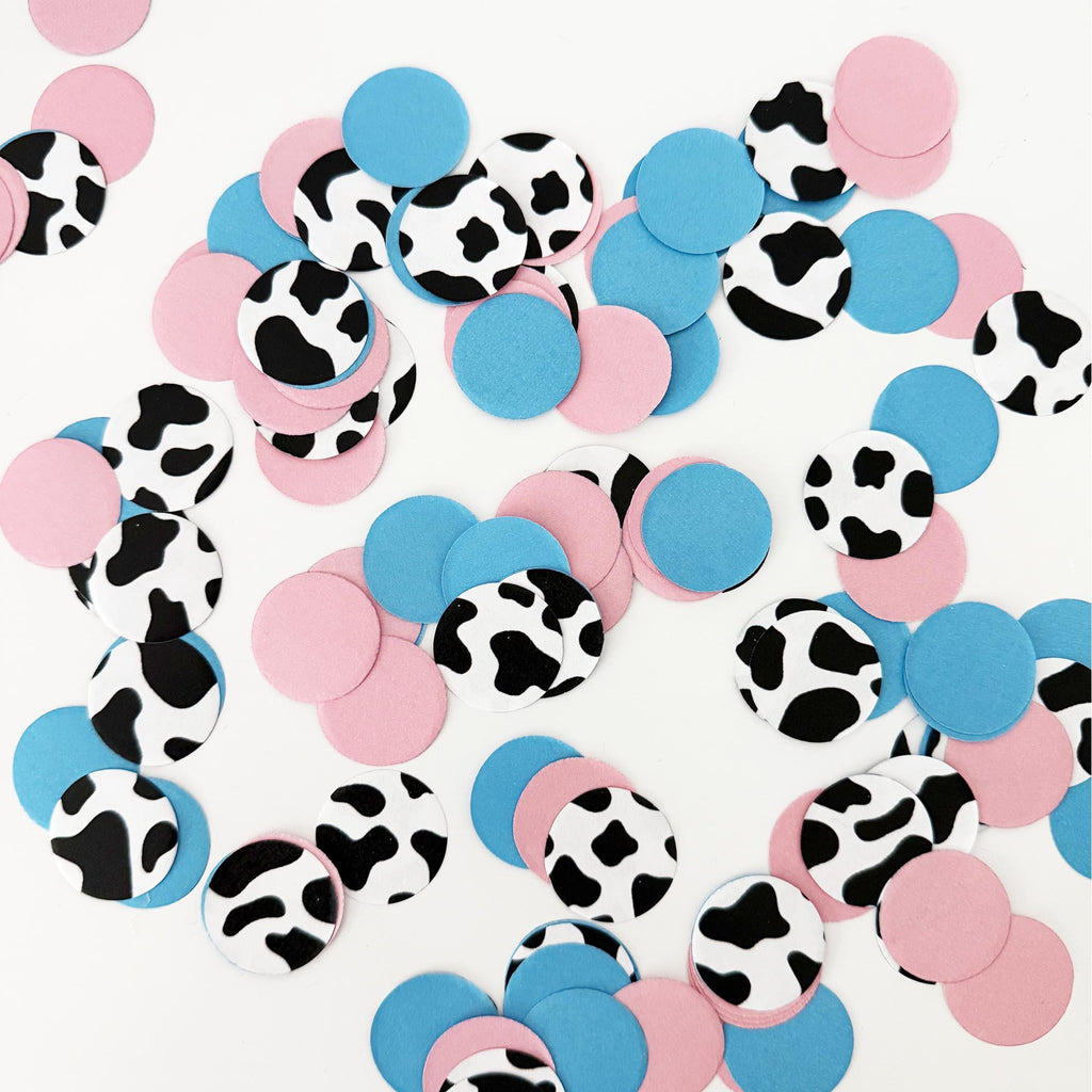 a collection of colorful confetti shapes, including pink, blue, and black and white cow-shaped pieces, scattered across a white background.