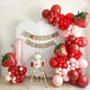 A festive birthday setup with a strawberry theme, a banner reading "My Berry Birthday" and a cake topper, a high chair banner . The decorations include large red and pink balloons, a balloon arch, and a balloon tower.