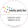 The image is a circular logo for a company called "swanky party box". The logo features a colorful design of triangles in various colors, and the company name is written in bold black text. Below the logo, the company's slogan "CUSTOM EVENT SUPPLIES HANDMADE IN THE USA" is written in a smaller font. The website "www.swankypartybox.com" is also included in the image.