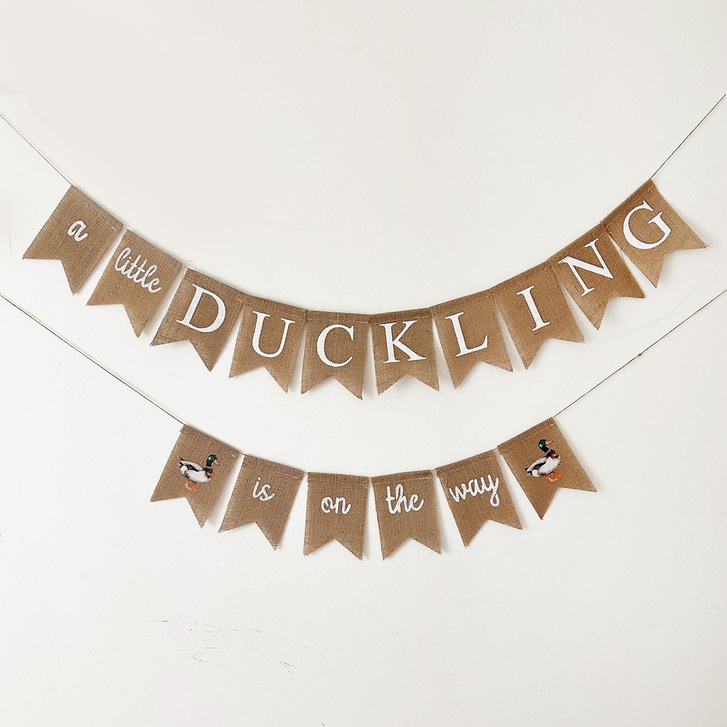 A banner with the text "a little duckling is on the way" hanging on a wall.