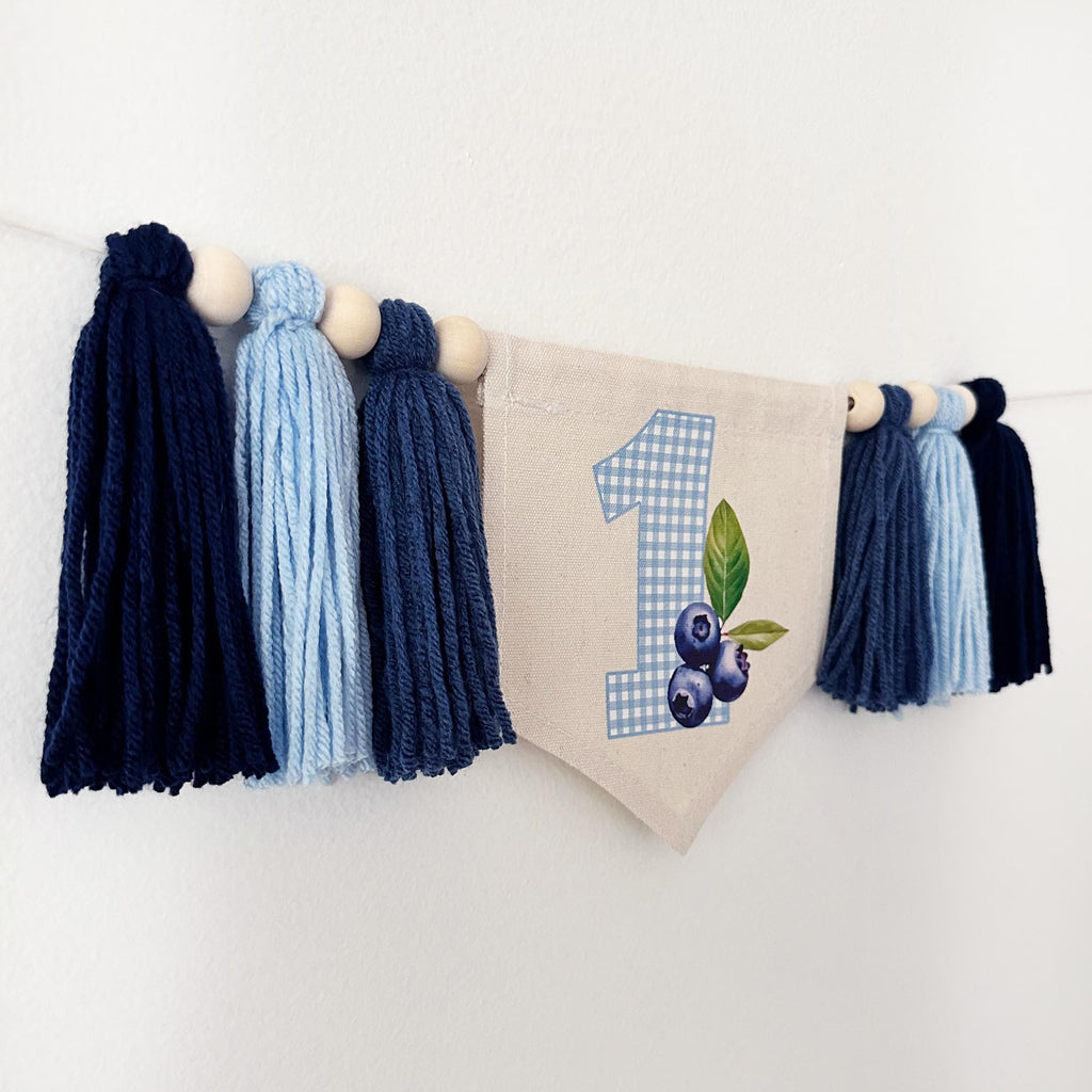 A banner with tassels and a blue and white checkered number 1, along with blue and white tassels, is displayed on a white wall.