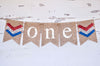 A banner with the word "ONE" written on it, made of burlap and decorated with patriotic colors.