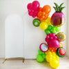 A colorful balloon arrangement decorated with different fruit balloons, including a pineapple, kiwi, and other assorted fruits, is displayed against a white wall.