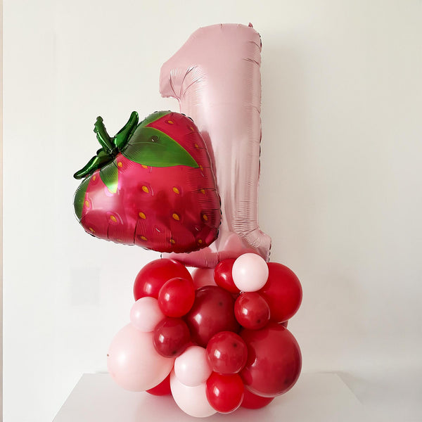 A balloon bouquet consisting of a large pink balloon with a green stem and a smaller red balloon, along with numerous red and pink balloons, creating a visually appealing arrangement.