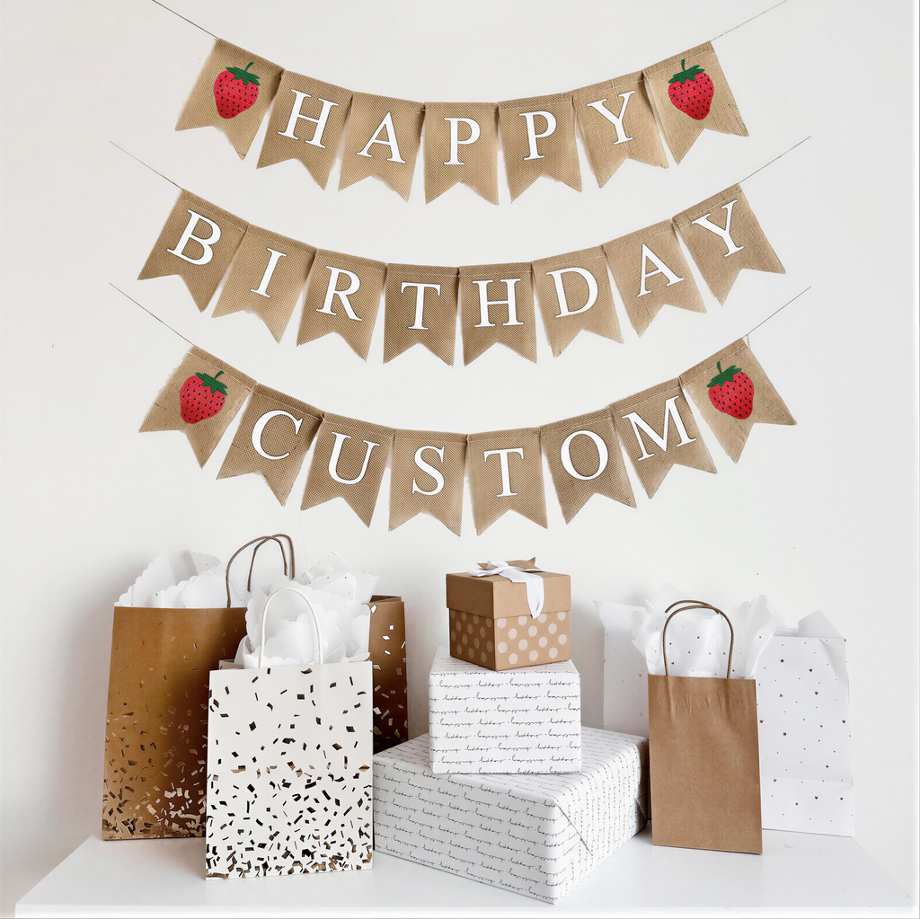 A happy birthday burlap banner strung on two or three strings. The happy is at the top and the birthday below.  Hand painted strawberries are at the beginning and end of the word happy.  The strawberries are painted in red with a green stem and black seeds. This banner has the option to add a third line with a custom name or saying with two additional strawberry image flags.