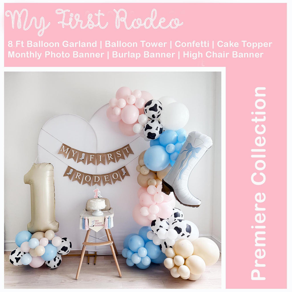 The image is a pink, white and blue color scheme featuring a balloon tower, a balloon garland, and a cake topper. The scene shows a full set up of a my first rodeo party kit.
