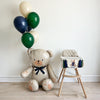 A large teddy bear balloon next to a high chair with a matching high chair banner.