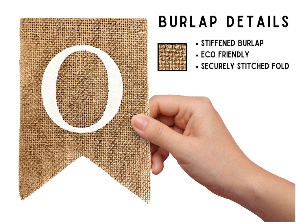 a hand holding a burlap banner with a large white letter "O" on it. The banner is described as "Stiffened Burlap" and "ECO Friendly" and "SECURELY STITCHED FOLD", indicating that it is made from environmentally friendly materials and has been securely stitched.