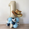 A large number one balloon is surrounded by various blue and white balloons, including some with cow designs, creating a festive and celebratory display.