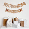 A festive scene with a banner that reads "a little COWBOY is on the way" and various gift bags and boxes arranged on a white surface.