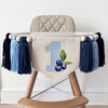 A high chair banner displaying a blue gingham printed number 1 and blueberries hanging from the side.