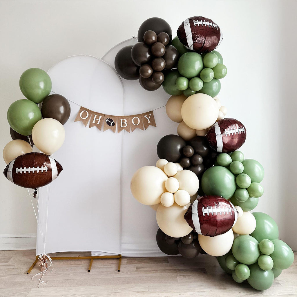 A balloon arch in the shape of a football, with various colored balloons, including green, brown, and white, arranged in a decorative manner.