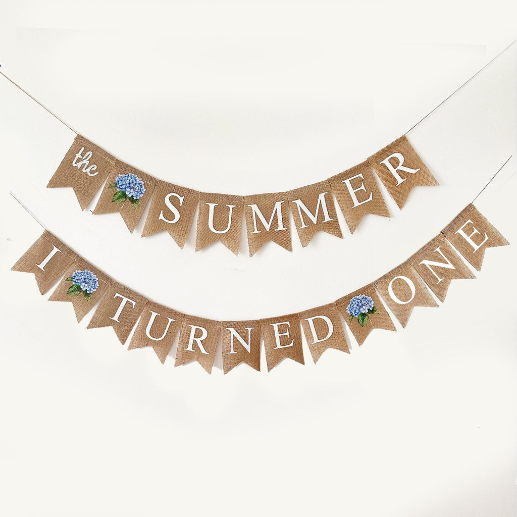 A banner with the text "The summer turned one" written on it, along with a blue flower decoration.