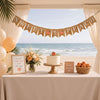 a beachside baby shower setup with a banner reading "Sweet as Peach" and a table with a cake, flowers, and a basket of peaches.