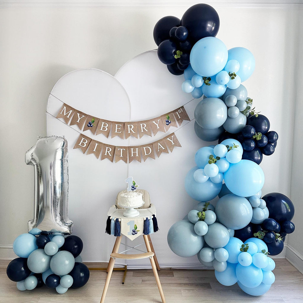 a birthday celebration setup with a cake, balloons, and a banner.