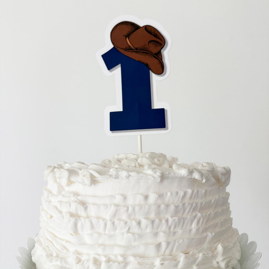 A white cake with a blue number one candle on top.
