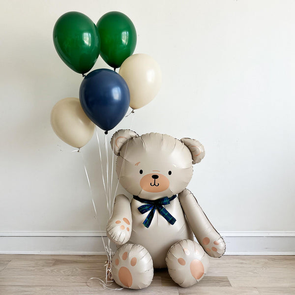 A large teddy bear balloon holding a bunch of classic blue, dark green and beige balloons.