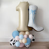 A balloon tower with a large number 1 balloon and a white cowboy boot balloon, creating a playful and festive atmosphere.