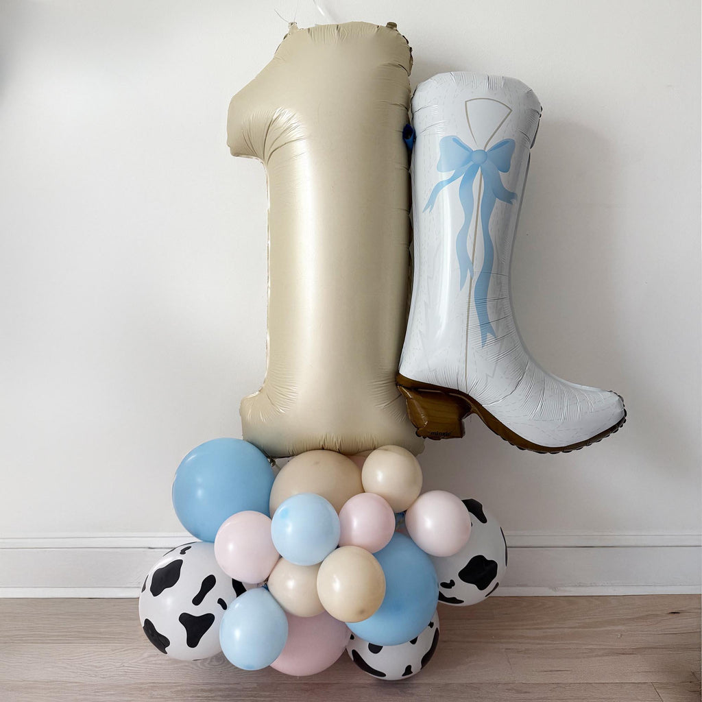 A balloon tower with a large number 1 balloon and a white cowboy boot balloon, creating a playful and festive atmosphere.