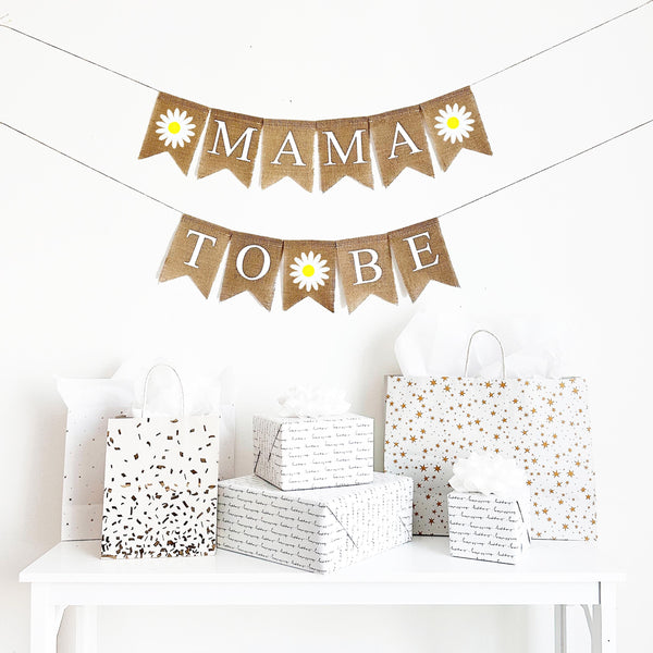 Burlap Daisy Mama to Be baby shower banner.In white lettering, this banner spells out the words mama to be with a hand stenciled daisy flag between each word. Perfect for a boho groovy baby shower.