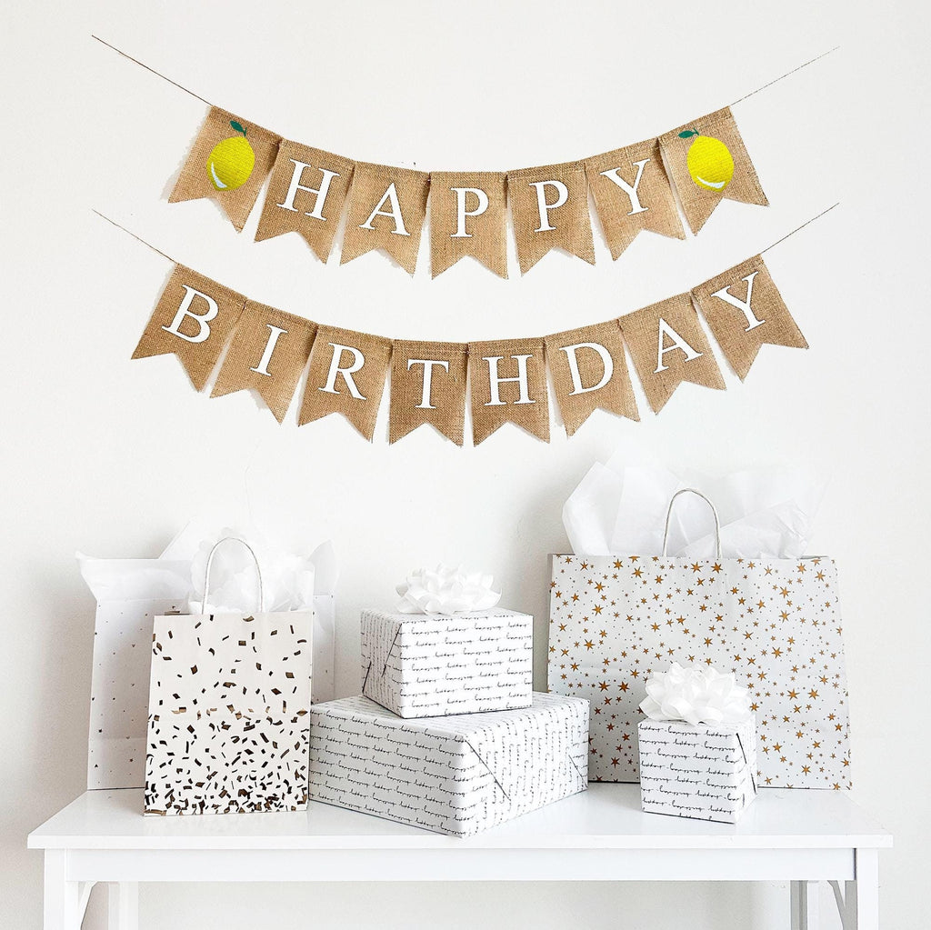 This is a burlap banner with individual fishtail shaped flags. The top line has 7 flags with the word HAPPY in white letters with a lemon on either end of the word. The bottom line has the word BIRTHDAY in white letters.