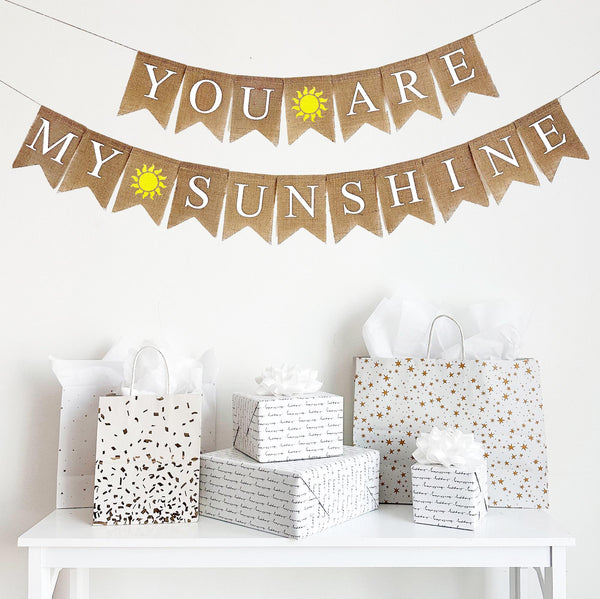 A two tiered burlap banner with the first line reading you are with a hand painted yellow sunshine between the words. The second tier reads my sunshine with the same yellow sunshine between the words.