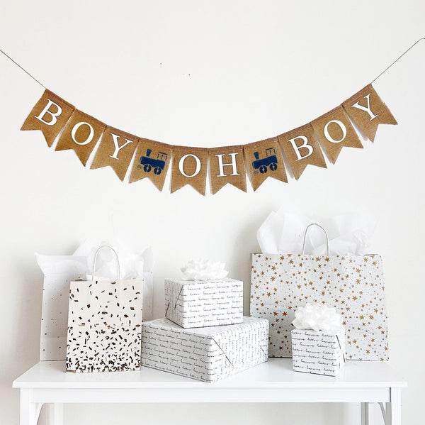 A burlap banner reading boy oh boy with navy train images between the words.
