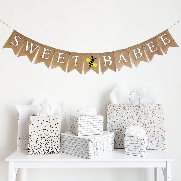 A burlap banner reading sweet babee with a yellow and black bumblebee image  between the words.