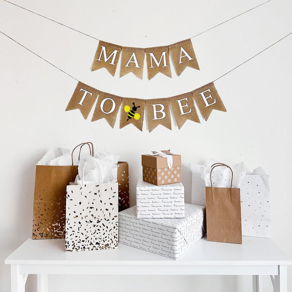 A two tiered burlap banner. The first tier reads mama. The second tier reads to bee with a yellow and black bee icon between the words.