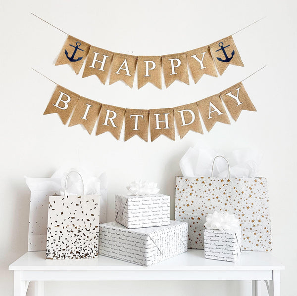 This is a burlap banner made from fishtail shaped flags. Each flag has a white letter painted on it. The top string says HAPPY with a navy anchor on either end. The bottom string says BIRTHDAY. Each flag measures 4.5 by 6.5 inches in size.
