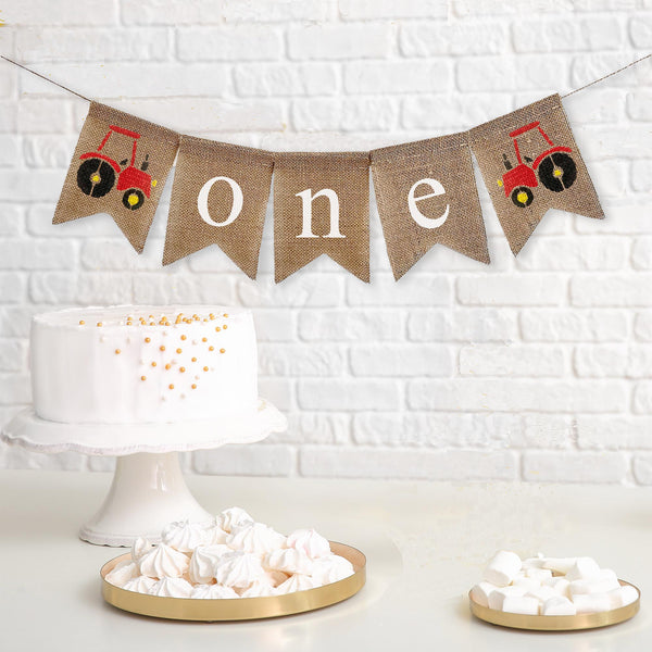 This is a burlap banner made of 4.5 by 6.5 inch fishtail shaped flags. The word ONE is spelled out in white lowercase letters. There is a hand stenciled image of a red tractor on either end.