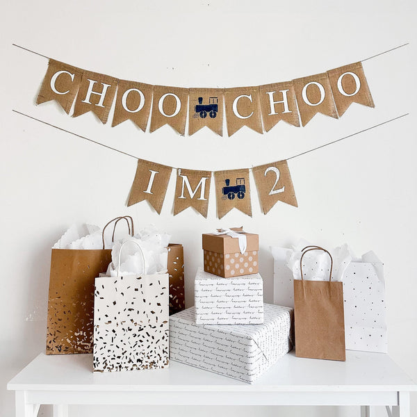 A two tiered burlap banner. The first tier reads choo choo with a navy blue train between the words. The second tear reads I&#39;m 2 with the same navy blue train image between the words.