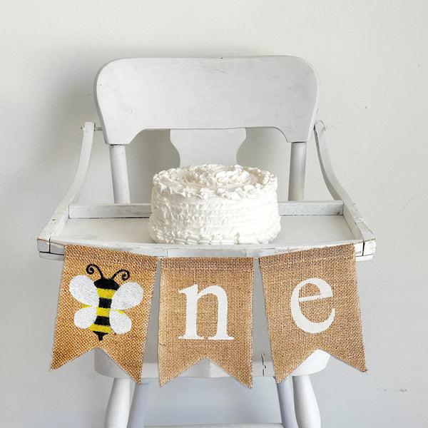 A burlap banner with a bumblebee with white wings as the O and a n and e flag.