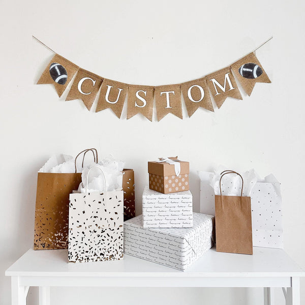 This is a burlap banner made from 4.5 by 6.5 inch fishtail shaped flags. Each flag has a white stenciled letter on it. The sample spells CUSTOM but you can add any letters you&#39;d like to spell a word. There is a stenciled football image on each end.