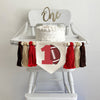 A 5 by 7 inch canvas flag with a large red number1 with a brown football propped beside it. On each side of the flag are a red, tan and brown 5 inch yarn tassel. Each tassel is separated by a wooden bead.