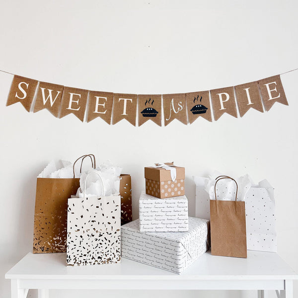 A burlap banner reading sweet as pie with two pie images.