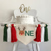 A 5 x 7 canvas center flag with a cute reindeer head to make the O followed by the letters NE in green which makes the word ONE. There is a red, white and dark green 5 inch yarn tassel on each side, each separated by a wooden bead.