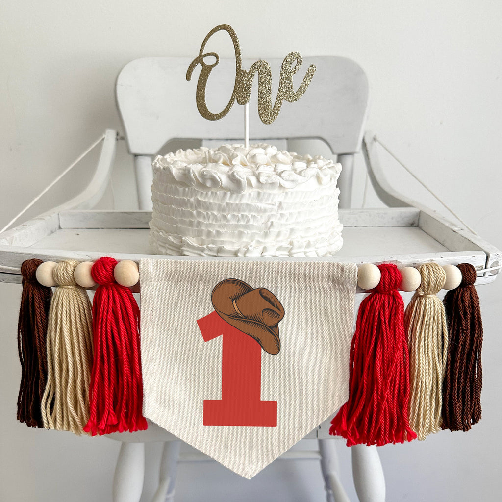 A 5 by 7 inch canvas center flag with a large red number 1 topped by a brown cowboy hat. On each side there is a 5 inch red, tan and brown yarn tassel, each separated by a wooden bead for a total of 6 tassels.