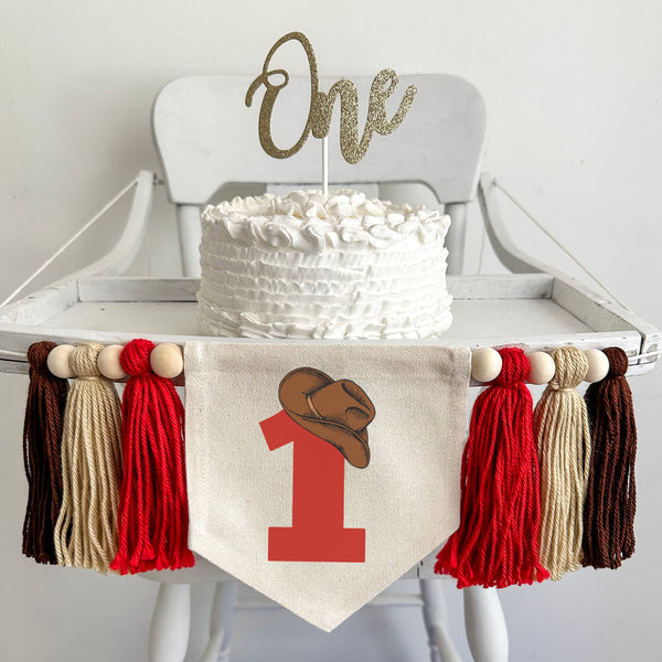 A 5 by 7 inch canvas center flag with a large red number 1 topped by a brown cowboy hat. On each side there is a 5 inch red, tan and brown yarn tassel, each separated by a wooden bead for a total of 6 tassels.