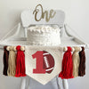 A 5 x 7 canvas flag with a large red number 1 with a brown football propped against it. On each side there is a red, tan and brown 5 inch yarn tassel, each separated by a wooden bead for a total of 6 tassels and 6 beads.