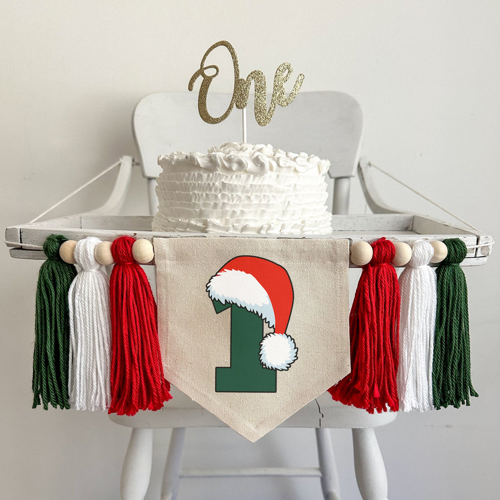 A 5 x 7 canvas center flag with a dark green number 1 with a Santa hat sitting on top of it. On each side there is a red, white and dark green 5 inch yarn tassel, each separated by a wooden bead for a total of 6 tassels and 6 beads.