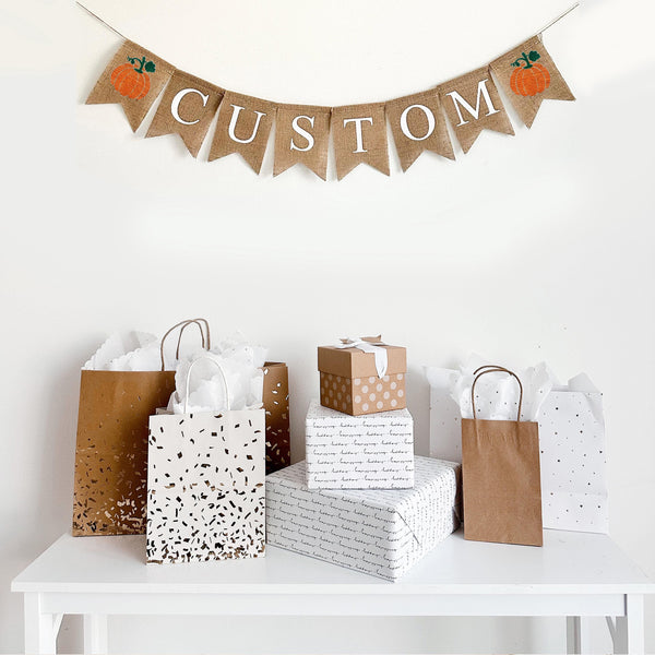 Create a custom burlap banner with hand stenciled orange pumpkins. A one line burlap banner with white letters to spell out any word or name with an orange pumpkin on each side. The perfect addition to a fall celebration.