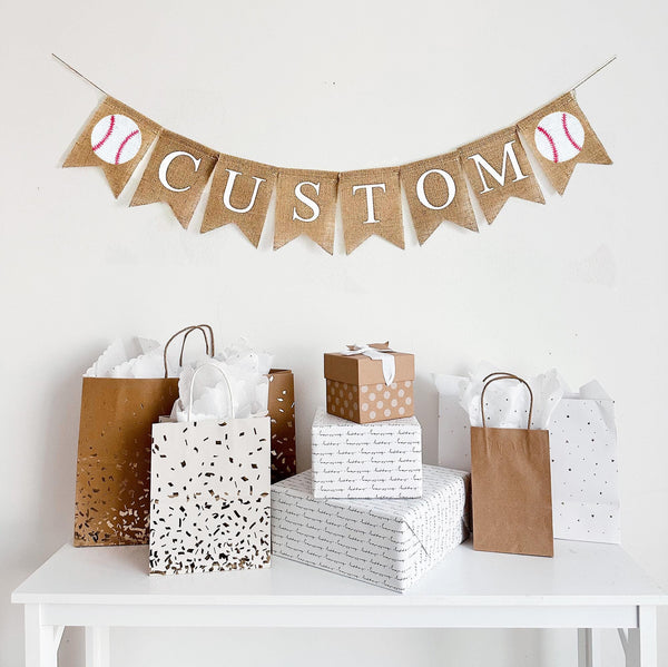 A burlap banner made from 4.5 by 6.5 inch fishtail shaped flags. There is an image of a baseball on either end. Choose your own custom name or word in white capital letters to personalize your banner.
