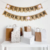 A burlap banner made from 4.5 by 6.5 inch fishtail shaped flags. The top line can be customized with a name in black letters and has a baseball image on each end. The bottom line says ROOKIE YEAR in black letters and has a baseball in the middle.