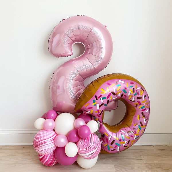 This donut themed second birthday balloon tower features a pastel pink number 2 balloon, a jumbo 36 inch pink donut balloon on top of a pink latex balloon tower.