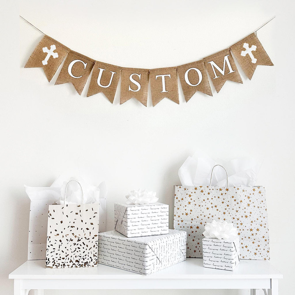 This burlap banner is customizable to say anything you want. Accented with your choice of pink, white or blue crosses, this banner is the perfect way to celebrate Easter, a Christening, First Communion, or any religious celebration. With hand stenciled crosses flanking white lettering, this burlap banner can pair with any theme.