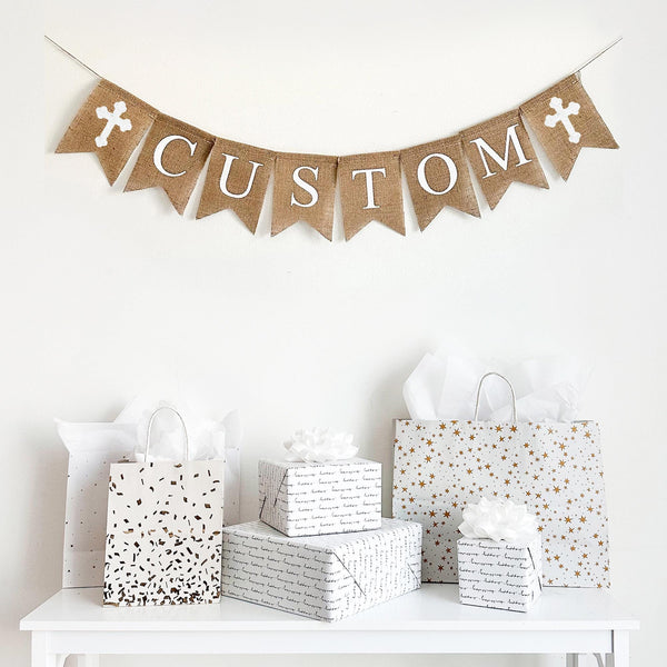 This burlap banner is customizable to say anything you want. Accented with your choice of pink, white or blue crosses, this banner is the perfect way to celebrate Easter, a Christening, First Communion, or any religious celebration. With hand stenciled crosses flanking white lettering, this burlap banner can pair with any theme.