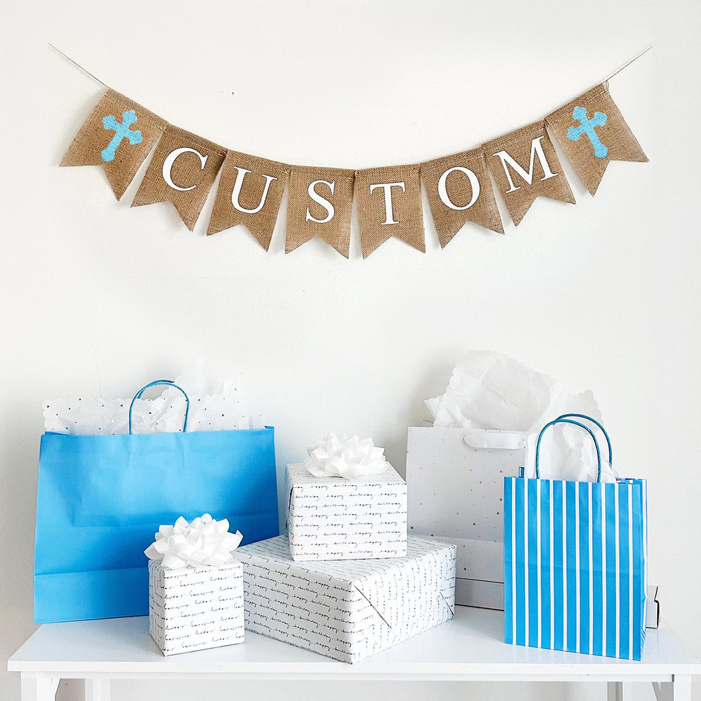 This burlap banner is customizable to say anything you want. Accented with your choice of pink, white or blue crosses, this banner is the perfect way to celebrate Easter, a Christening, First Communion, or any religious celebration. With hand stenciled crosses flanking white lettering, this burlap banner can pair with any theme.