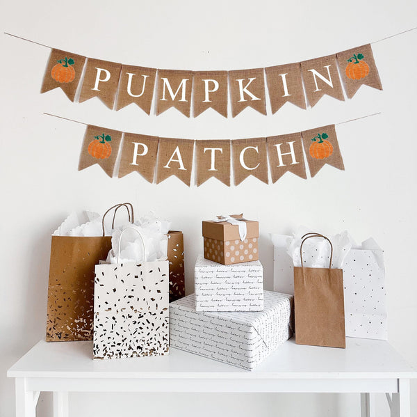 A burlap banner made from 4.5 by 6.5 inch fishtail shaped flags. The top string says PUMPKIN in white capital letters with an orange pumpkin with a green stem on each end. The bottom string says PATCH in white capital letters with an orange pumpkin with a green stem on each end.