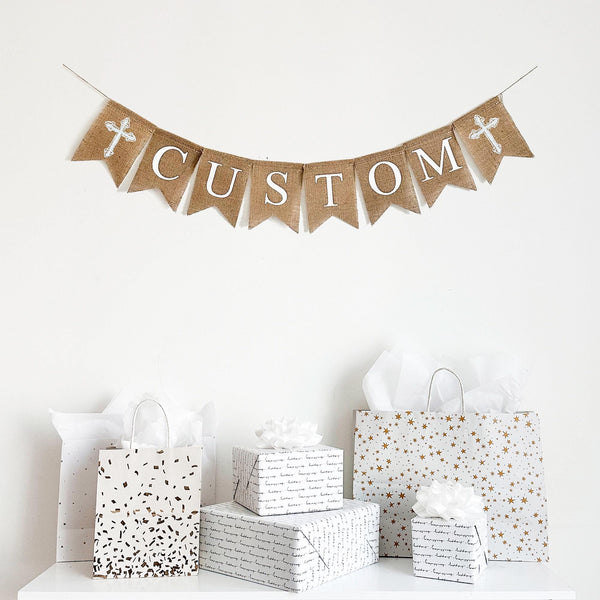 This personalized religious banner features two white crosses on either end of a customizable burlap banner. Add a name, date or special phrase to add a personalized touch to your celebration.